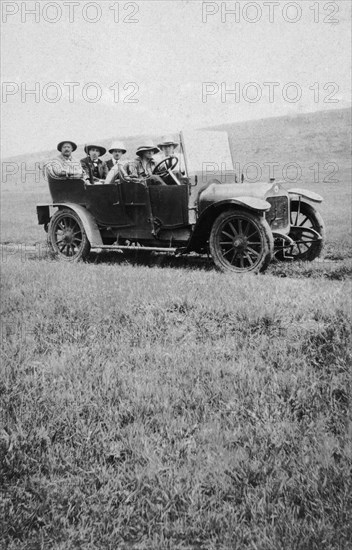 Car crosses the veldt. Five European men in an open-topped car drive along a rough track in rolling, open countryside, otherwise known as 'veldt' land (grassland equivalent to the pampas of South America). Nakuru, British East Africa (Kenya), 1920. Nakuru, Rift Valley, Kenya, Eastern Africa, Africa.