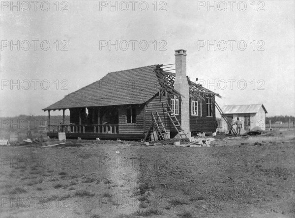 Building a house. This is the third in a series of four photographs showing the rapid erection of a timber-framed European-style house. The house was built for Charles Bungey, a training officer with the Kenyan Public Works Department, by the local apprentices of his department. Nakuru, Kenya, March 1922. Nakuru, Rift Valley, Kenya, Eastern Africa, Africa.
