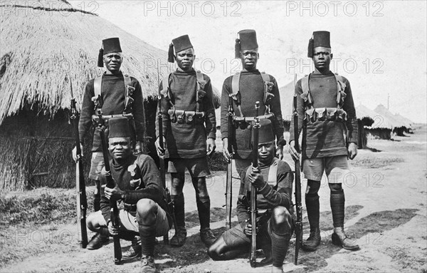 Recruits for the 2nd King's African Rifles. Six uniformed recruits in the King's African Rifles pose holding guns. British East Africa (Kenya), circa 1916. Kenya, Eastern Africa, Africa.