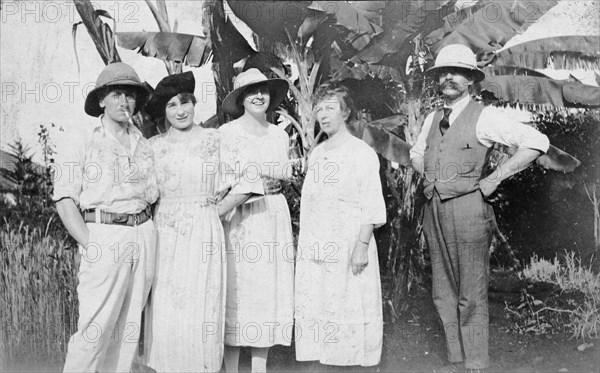 The Powis family. Informal group shot of a European family standing in front of a clump of banana palms. The man on the right is identified as 'Papa Powis'. British East Africa (Kenya), circa 1920. Kenya, Eastern Africa, Africa.