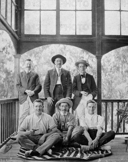 Men on a zebra skin rug. Informal group portrait of six European men on the wooden veranda of a colonial house, three of whom are sitting on a preserved zebra skin. British East Africa (Kenya), circa 1910., Nairobi Area, Kenya, Eastern Africa, Africa.