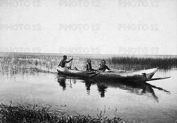 Canoe on Lake Victoria. Three men paddle a canoe through the shallows of the lake. Lake Victoria, British East Africa (Kenya), circa 1915., Nyanza, Kenya, Eastern Africa, Africa.