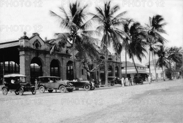 Mackinnon Market at Mombasa. Cars and palm trees line Digo Road in front of Mombasa's municipal market hall, Mackinnon Market. Mombasa, Kenya, 1927. Mombasa, Coast, Kenya, Eastern Africa, Africa.