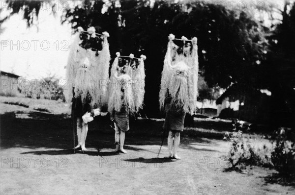 Nandi youths wearing circumcision masks. Three Nandi youths wear tall, elaborate grass headdresses and masks during their circumcision rites. Kapsabet, Kenya, February 1928. Kapsabet, Rift Valley, Kenya, Eastern Africa, Africa.