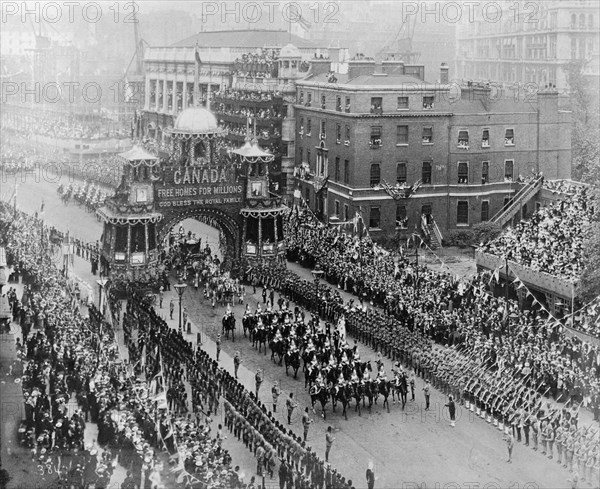 Coronation celebrations for Edward VII. The royal carriage proceeded by mounted soldiers passes through the arch of an elaborately decorated float that reads 'Canada, Free Homes for Millions, God Bless the Royal Family' at Edward VII's coronation procession. The parade is flanked by military men in uniform and an enormous crowd of onlookers cheer and wave as it passes. London, England, 9 August 1902. London, London, City of, England (United Kingdom), Western Europe, Europe .