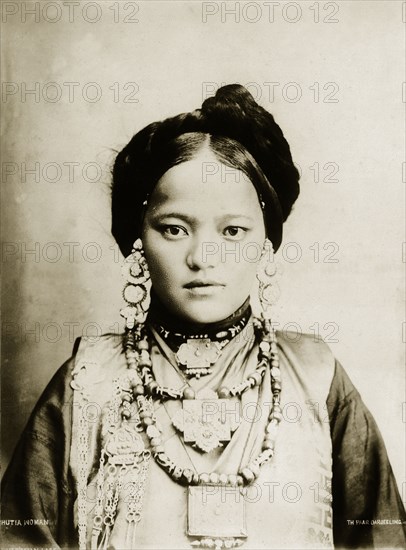 Bhutia woman. Portrait of a finely dressed young Bhutia woman in traditional costume. Her hair is worn up and she wears ornate earrings and several heavily beaded necklaces. Darjeeling, India, circa 1900. Darjeeling, West Bengal, India, Southern Asia, Asia.