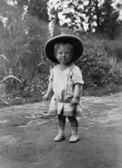 Child wearing a solatopi. Portrait of Allan Kidney as a toddler wearing a solatopi and belted dress. Blantyre, Nyasaland (Malawi ), circa 1910. Blantyre, Blantyre, Malawi, Southern Africa, Africa.