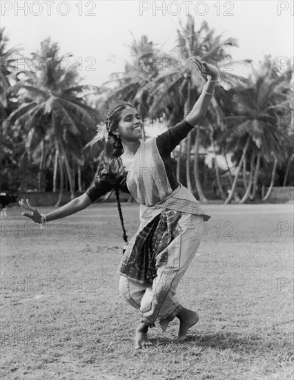 Sri Lankan tamil dancer. A young Tamil woman smiles as she performs a traditional dance outdoors. Her hair is plaited into a long braid and she wears traditional costume. Jaffna, Ceylon (Sri Lanka), 1957. Sri Lanka, Southern Asia, Asia.