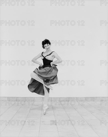 Daphne Dale as Carmen. Dancer Daphne Dale poses for the camera balancing on one toe. Playing the role of Carmen, she is dressed in theatrical dance costume and wears ballet shoes. Kenya, 15 November 1955. Kenya, Eastern Africa, Africa.