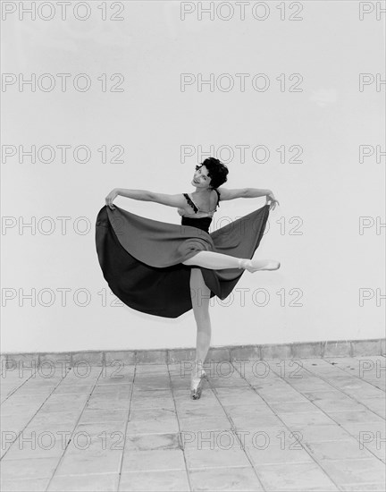 Daphne Dale as Carmen. Dancer Daphne Dale poses for the camera balancing on one toe. Playing the role of Carmen, she is dressed in theatrical dance costume and wears ballet shoes. Kenya, 15 November 1955. Kenya, Eastern Africa, Africa.