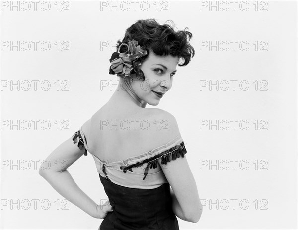 Portrait of Daphne Dale. Dancer Daphne Dale gazes provocatively into the camera. Playing the role of Carmen, she is dressed in theatrical costume, sporting a low cut bodice with bare arms and a decorative flower in her hair. Kenya, 15 November 1955. Kenya, Eastern Africa, Africa.