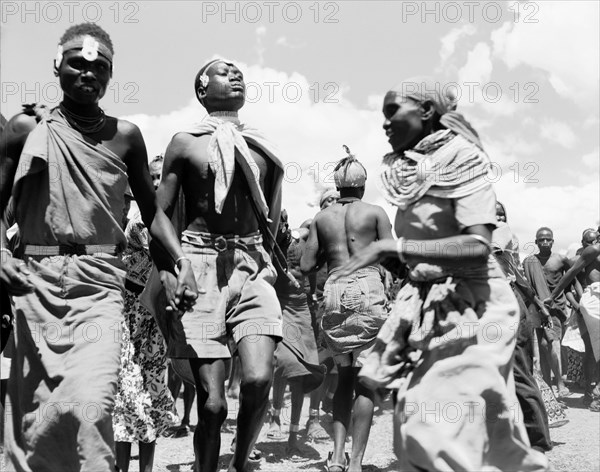 Turkana dancers. Two Turkana men hold hands in the midst of a traditional dance involving both men and women. They wear decorative headbands, a typical feature of Turkana dress. Kenya, 26 November 1955. Kenya, Eastern Africa, Africa.