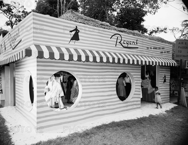 Regent stand at the Royal Show. The novel exterior of the Regent outfitters stand at the Royal Show. The Regent logo appears above the doorway and female customers can be seen browsing clothes through the circular windows. Nairobi, Kenya, 28 September-1 October 1955. Nairobi, Nairobi Area, Kenya, Eastern Africa, Africa.