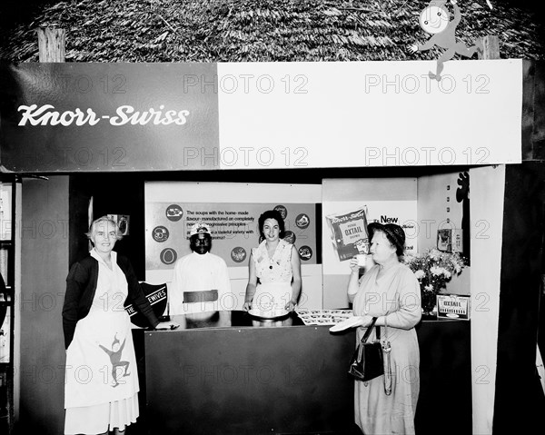 Knorr-Swiss stand at the Royal Show. A European woman samples a cup of soup from a Knorr-Swiss stall at the Royal Show. Nairobi, Kenya, 28 September-1 October 1955. Nairobi, Nairobi Area, Kenya, Eastern Africa, Africa.
