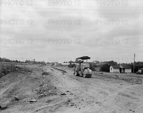 Road under construction. A lone man in a steamroller on the construction site of a new road. Kenya, 5 September 1955. Kenya, Eastern Africa, Africa.
