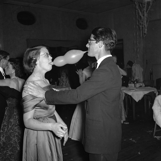 Balloon antics. A formally dressed couple clown around with a balloon at a dance held for the Sports Journalists Association of Kenya (SJAK). Kenya, 19 August 1955. Kenya, Eastern Africa, Africa.