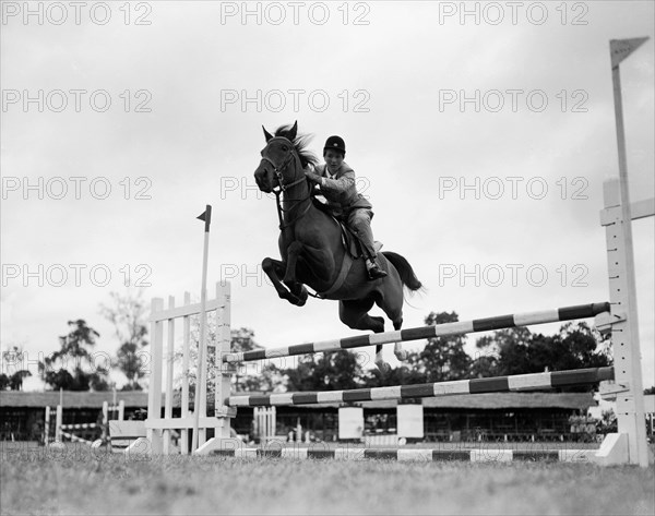 El Wak' jumps a fence. Juliet Colville jumps a fence on a horse called 'El Wak' in the juvenile handicap jumping competition at the SJAK show (Sports Journalists Association of Kenya). Kenya, 20 August 1955. Kenya, Eastern Africa, Africa.