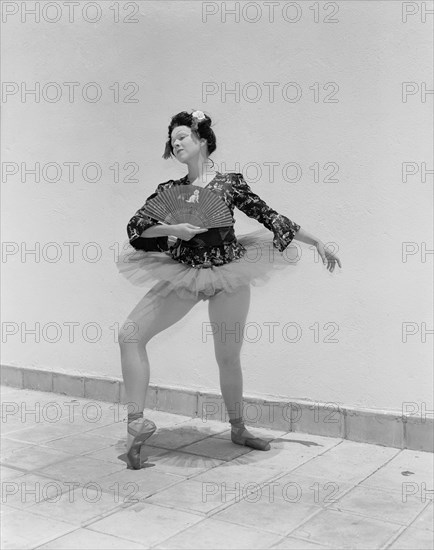 Sonja in Japanese costume. Sonja poses wearing theatrical costume comprising a tutu and ballet shoes teamed with a Japanese-style top. Her blonde hair is tucked under a dark Geisha-style wig and her oriental look is completed with theatrical make up and a decorative fan. Kenya, 4 November 1955. Kenya, Eastern Africa, Africa.