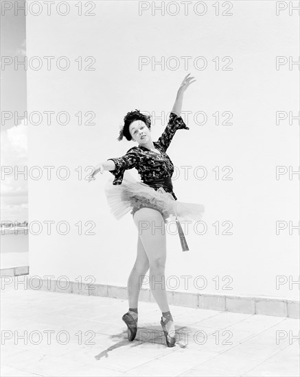 Sonja in Japanese costume. Sonja poses wearing theatrical costume comprising a tutu and ballet shoes teamed with a Japanese-style top. Her blonde hair is tucked under a dark Geisha-style wig and her oriental look is completed with theatrical make up and a decorative fan. Kenya, 4 November 1955. Kenya, Eastern Africa, Africa.