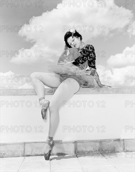 Sonja in Japanese costume. Sonja poses wearing theatrical costume comprising a tutu and ballet shoes teamed with a Japanese-style top. Her blonde hair is tucked under a dark Geisha-style wig and her oriental look is completed with theatrical make up and a decorative fan. Kenya, 4 November 1955. Kenya, Eastern Africa, Africa.