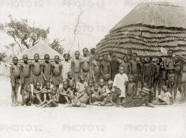 Balanda children. A large group of semi-naked Balanda children gather for the camera outside a thatched village hut. Sudan, circa 1930. Sudan, Eastern Africa, Africa.