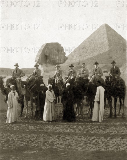 Visiting the Sphinx, circa 1924. A group of European men, probationers in the Sudan Political Service, pose for the camera on camels in front of the Sphinx and pyramids. Giza, Egypt, circa 1924. Giza, Giza, Egypt, Northern Africa, Africa.