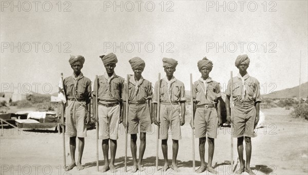 African scout group. A group of African men at a scout camp. Each carries a stick and wears a uniform consisting of short trousers, a shirt and neckscarf. Sinkat, Sudan, 1926. Sinkat, Red Sea, Sudan, Eastern Africa, Africa.