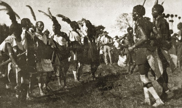 African dancers in costume. A group of African men dressed in ceremonial costume and feathered headdresses prepare to perform a traditional dance. Nairobi, Kenya, 12-17 January 1924. Nairobi, Nairobi Area, Kenya, Eastern Africa, Africa.