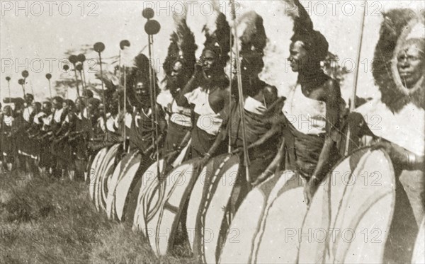 Chiefs prepare for a 'ngoma'. A group of African chiefs dressed in ceremonial costume hold sticks and patterned shields as they prepare to perform in a traditional 'ngoma'. Nairobi, Kenya, 12-17 January 1924. Nairobi, Nairobi Area, Kenya, Eastern Africa, Africa.