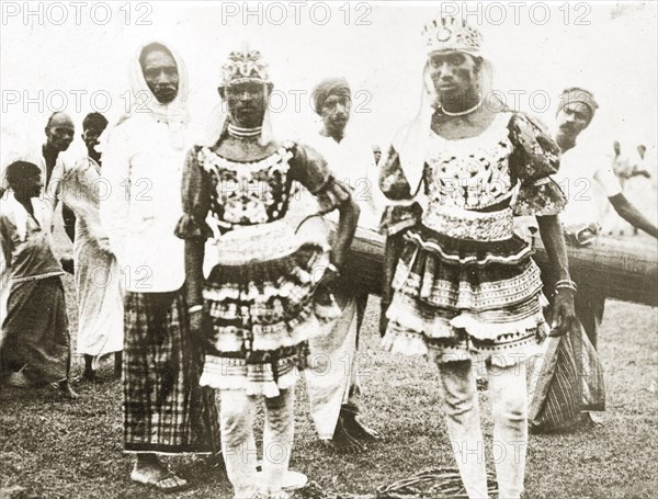 Ceylonian dancers. Two Ceylonian men dressed in traditional dance costumes wear ornate headdresses and patterned tunics heavily decorated with frills and puffed sleeves. Trincomali, Ceylon (Sri Lanka), 27-31 January 1924. Trincomali, East (Sri Lanka), Sri Lanka, Southern Asia, Asia.