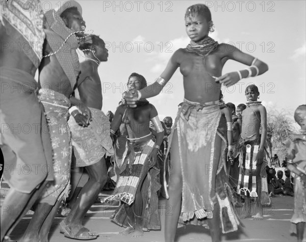 A Turkana 'ngoma'. A group of Turkana adults dance at a crowded 'ngoma'. They wear traditional dress and ornate jewellery including metal armrings, necklaces and earrings. Wamba, Kenya, 13 October 1956. Wamba, Rift Valley, Kenya, Eastern Africa, Africa.