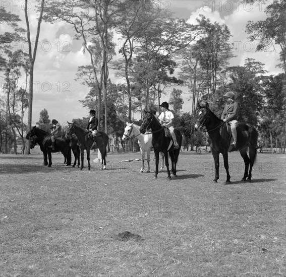 Pony riding competition. A row of children riding ponies line up in a field for the class one competition at the SJAK show (Sports Journalists Association of Kenya). Kenya, 25 August 1956. Kenya, Eastern Africa, Africa.