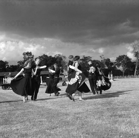 Square dancing at the SJAK show. Four couples wearing matching dance costumes perform a square dance in the arena at the SJAK show (Sports Journalists Association of Kenya). Kenya, 25 August 1956. Kenya, Eastern Africa, Africa.