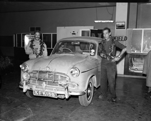 Nairobi to Capetown record run winners. Racing drivers John Manussis and Peter Davies pose beside a car wearing laurel wreaths around their necks after having completed the Nairobi to Capetown run in record time. Kenya, 6 September 1956. Kenya, Eastern Africa, Africa.