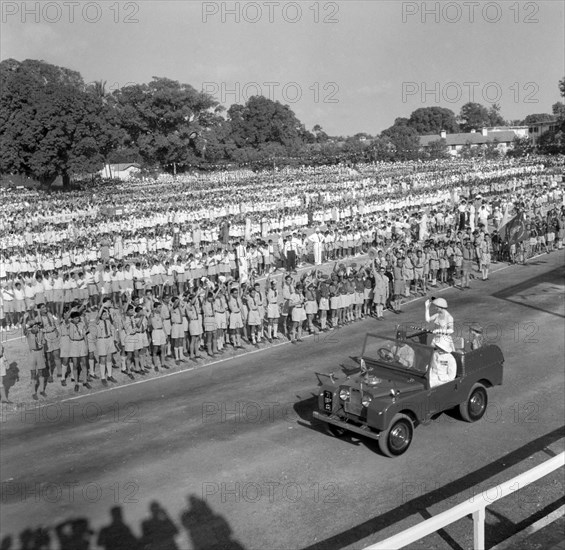 Kenyan schoolchildren welcome Princess Margaret. Princess Margaret waves to a large crowd of uniformed schoolchildren who stand in regimented lines as she is driven past them in a jeep. Mombasa, Kenya, 22 September 1956. Mombasa, Coast, Kenya, Eastern Africa, Africa.