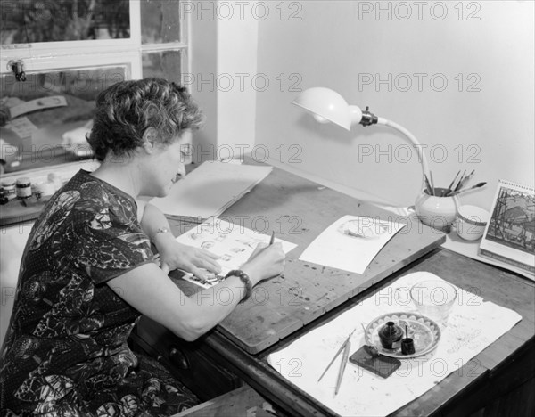 A book artist at work. Promotional shot for the East African Literature Bureau. An artist finishes drawings she has made for a new book. Her desk is equipped with inks, pens and paintbrushes. Kenya, 25 September 1956. Kenya, Eastern Africa, Africa.