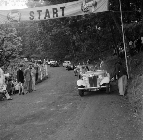 Starting line of the Brackenhurst Hill Climb. An MGTD sports car driven by Sacks, heads a line up of vehicles at the starting line of event number eight at the Brackenhurst Hill Climb. Limuru, Kenya, 30 September 1956. Limuru, Central (Kenya), Kenya, Eastern Africa, Africa.