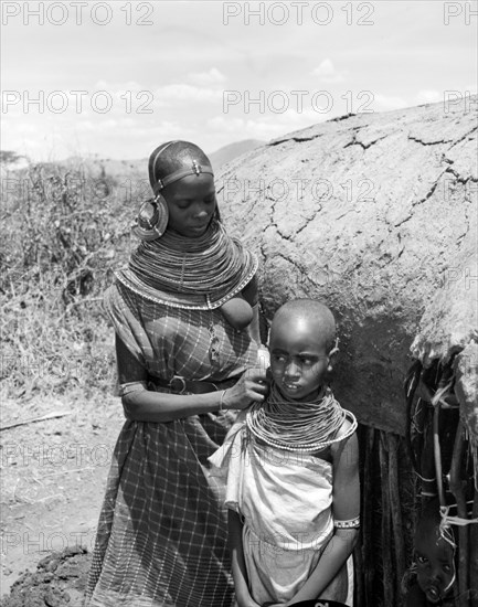 Samburu woman and child. A Samburu woman adjusts a child's necklace. She wears traditional dress and jewellery consisting of a heavily beaded necklace and striking, ornate earrings. Wamba, Kenya, 13 October 1956. Wamba, Rift Valley, Kenya, Eastern Africa, Africa.