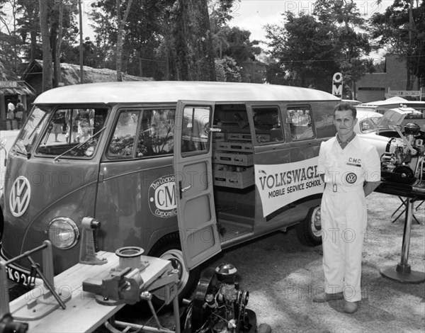Cooper Motors at the Royal Show. A uniformed Volkswagen attendent stands beside a Volkswagen van decorated with the words 'MOBILE SERVICE SCHOOL' at the Cooper Motors stand at the Royal Show. Kenya, 17 October 1956. Kenya, Eastern Africa, Africa.