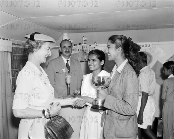 Coats & Clark prize winners. Two Indian girls are awarded trophies by a European Coats & Clark representative at the Royal Show. Kenya, 17-20 October 1956. Kenya, Eastern Africa, Africa.