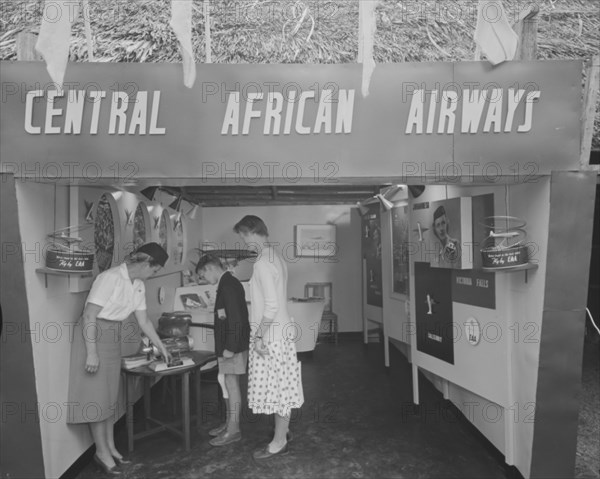 Central African Airways at the Royal Show. A woman dressed in a flight attendant's uniform shows visitors around the Central African Airways display stand at the Royal Show. Kenya, 17-20 October 1956. Kenya, Eastern Africa, Africa.