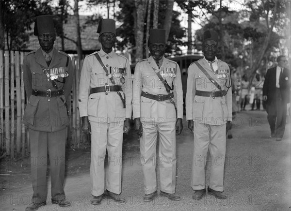 Long service askaris. Four highly decorated, long service askaris (soldiers) pose for the camera wearing their military uniforms at the Royal Show. Kenya, 17-20 October 1956. Kenya, Eastern Africa, Africa.