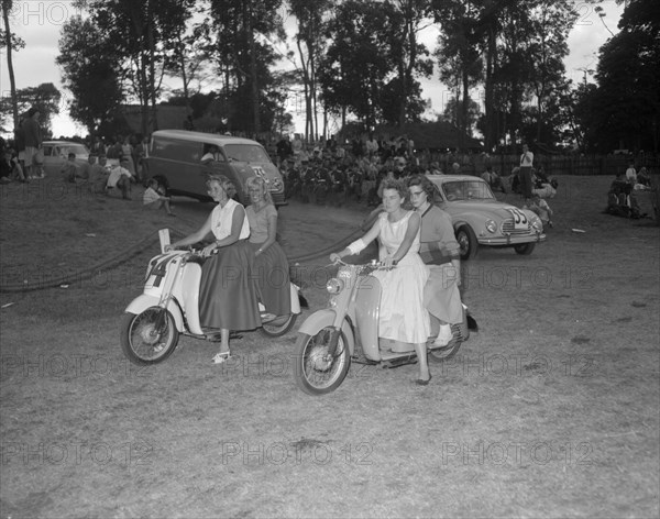 Scooters at the Royal Show. Four European women ride doubles on motor scooters at a vehicle parade at the Royal Show. Kenya, 17-20 October 1956. Kenya, Eastern Africa, Africa.