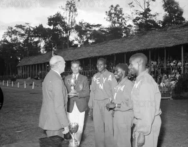 The Kenyan Olympic team at the Royal Show. Onlookers in a spectator stand at the Royal show watch as members of the 1956 Kenyan Olympic team are presented with a trophy. Kenya, 17-20 October 1956. Kenya, Eastern Africa, Africa.