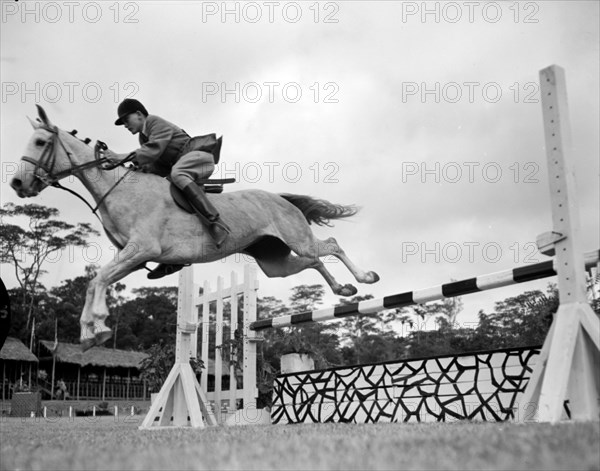 Cecil Walker rides 'Stella'. Cecil Walker rides his horse 'Stella' over a jump at the juvenile jumping competition at the Royal Show. Kenya, 17-20 October 1956. Kenya, Eastern Africa, Africa.