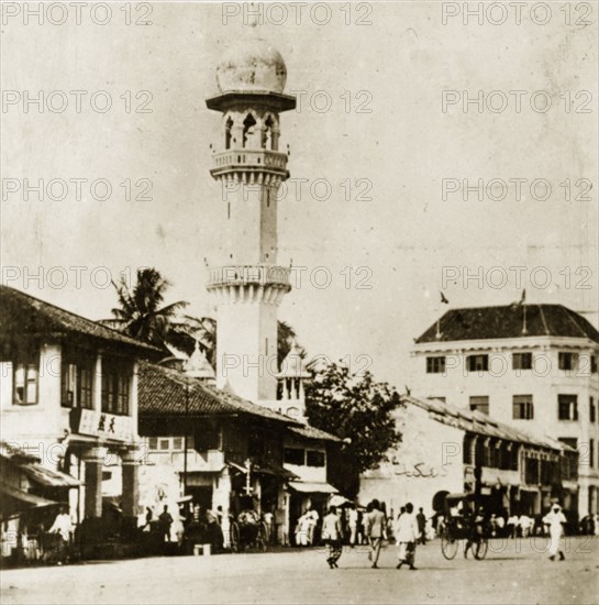 Kapitan Keling mosque. Penang street scene featuring the prominent yellow-domed minaret of the Kapitan Keling mosque. Georgetown, British Malaya (Malaysia), 4-8 February 1924. Georgetown, Penang, Malaysia, South East Asia, Asia.