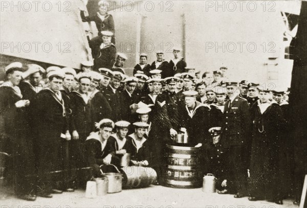 Barrel of rum. Uniformed naval personnel aboard HMS Repulse pose for a group portrait around a large barrel of rum decorated with the words 'THE KING, GOD BLESS'. Pacific Ocean between Hobart and Sydney, 4-8 April 1924., Tasmania, Australia, Australia, Oceania.
