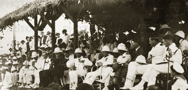 Naval officers watch a 'meke' dance. Admiral Field and other uniformed naval officers make up an audience for a 'meke', a kind of Fijian spiritual folk dance in which dancers' bodies are said to be possessed by spirits. Fiji, 21-27 May 1924. Fiji, Pacific Ocean, Oceania.