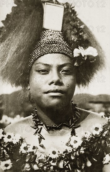 Wife of a Samoan chief. The wife of a Samoan chief wears traditional 'meke' costume. Her long hair is worn up, decorated with a beaded headdress, and her neck and shoulders are adorned with garlands of flowers (leis). Suva, Fiji, 21-27 May 1924. Suva, Viti Levu, Fiji, Pacific Ocean, Oceania.
