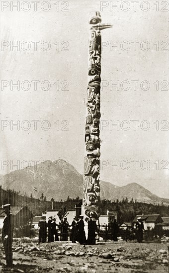 Native American totem pole. Sailors from the British Special Service Squadron stand beneath a native Amercian totem pole carved with pictograms of faces and various animals at Jasper Park. Victoria, Canada, 21 June-4 July 1924. Victoria, British Columbia, Canada, North America, North America .